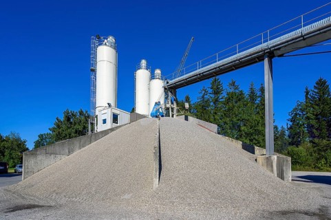 Steel silos and shovel crane with gravel piles and conveyor belt