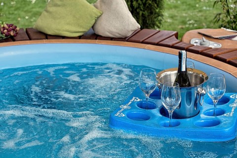Tray with champagne bucket and three glasses floating in a pool in the garden