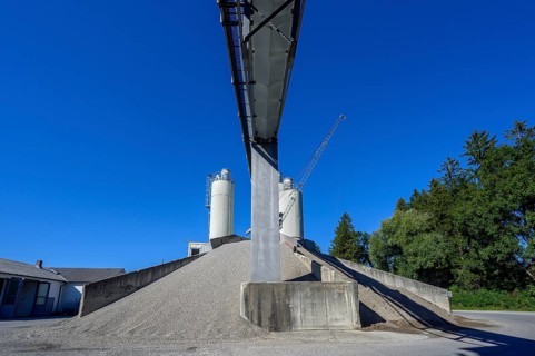 Steel silos and shovel crane with gravel piles and conveyor belt