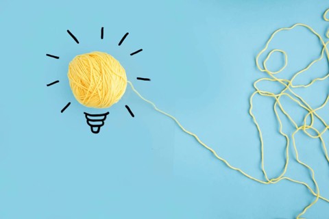 Illuminated yarn yellow light bulb blue background