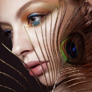 Beautiful girl with bright colored makeup and peacock feather on her face. Beauty face. Close-up. Photos shot in the studio