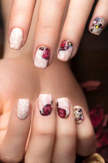 Beautiful manicure with flowers on female fingers. Nails design. Close-up. Picture taken in the studio on a white background