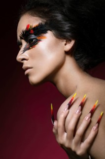 Beautiful girl in the image of the Phoenix bird with creative makeup and long nails. Manicure design. The beauty of the face. Photos shot in studio