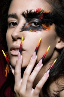 Beautiful girl in the image of the Phoenix bird with creative makeup and long nails. Manicure design. The beauty of the face. Photos shot in studio