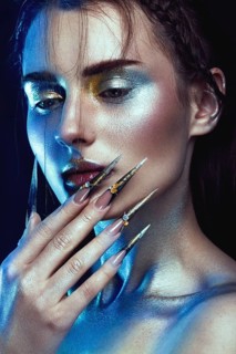 Beautiful girl with creative golden and silver glitter make-up and long nails art. The beauty of the face. Photos shot in studio