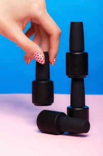 Black bottles of nail polish on a colorful background. Manicure design