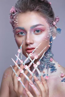 Beautiful girl in the image of a sweet fairy with art make-up and with long design nails. Creative manicure. Photo taken in the studio