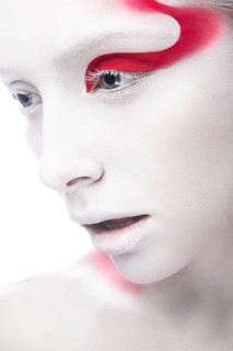 Art fashion girl with white skin and red paint on the face. Creative art beauty. Picture taken in the studio on a white background
