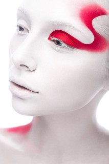 Art fashion girl with white skin and red paint on the face. Creative art beauty. Picture taken in the studio on a white background