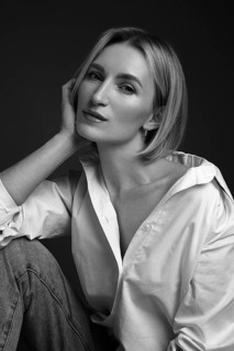 Beautiful blonde woman in a white shirt posing in the studio on a black background. Black and white photo. Model Tests