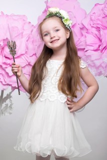 Little fairy girl in white dress on a background of flowers. Photo taken in studio