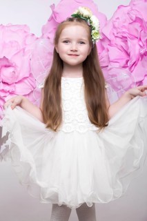 Little fairy girl in white dress on a background of flowers. Photo taken in studio