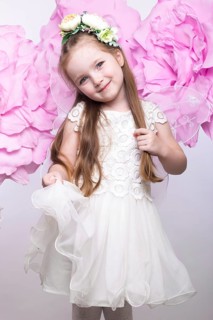 Little fairy girl in white dress on a background of flowers. Photo taken in studio