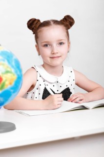 Little girl at the table of a first-grader. Photo taken in the studio