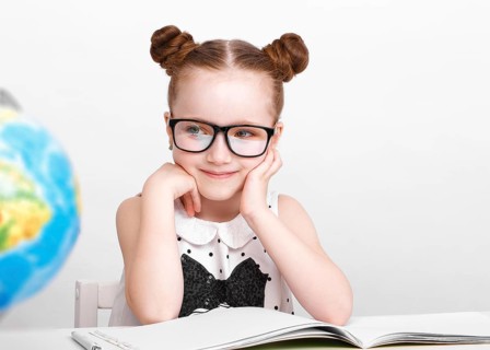 Little girl at the table of a first-grader. Photo taken in the studio
