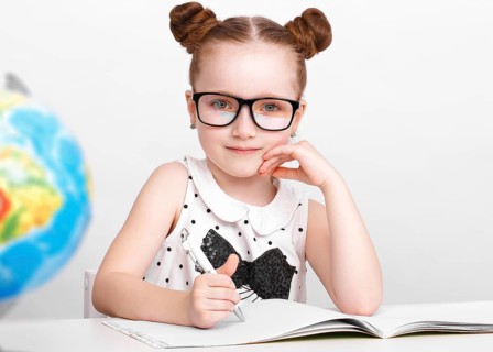 Little girl at the table of a first-grader. Photo taken in the studio