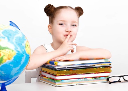 Little girl at the table of a first-grader. Photo taken in the studio