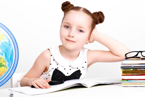 Little girl at the table of a first-grader. Photo taken in the studio
