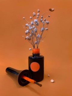 Black bottle of nail polish on a orange background with flowers. Manicure design