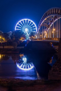 Illuminated Ferris wheel reflected in Elbe