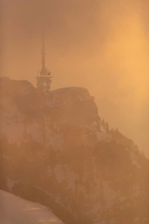 The transmission tower in the fog and warm light of the setting sun