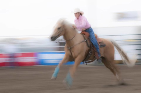 Motion blur of a cowgirl riding fast during barrel racing