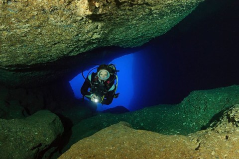 Diver sport diver swims in illuminated cave underwater cave
