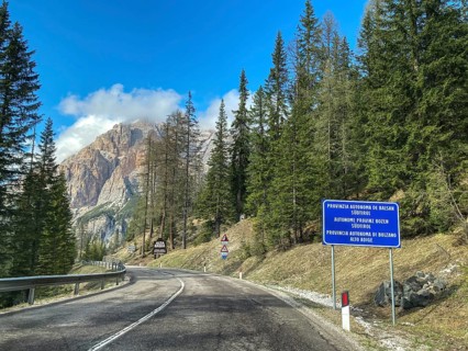 Mountain road behind Passo di Valparola with view of sign marking border between Veneto and Province of Bolzano South Tyrol