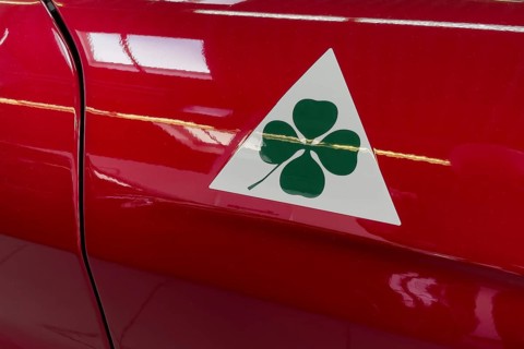 Historic modern signet logo marking Alfa Romeo Quadrifoglio green four-leaf clover on white triangle for sporty cars racing cars