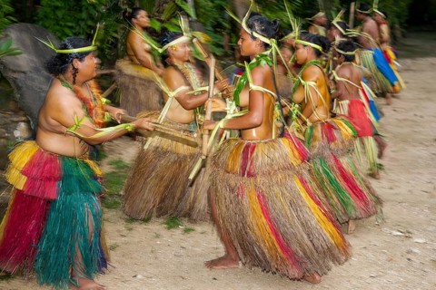 Traditional group of dancers from Yap Island dancing in historical dress headdress performing traditional ritual bamboo dance with bamboo sticks