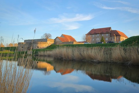 Renaissance moated castle with reflection in the pond and reed grass