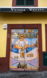 Colourfully painted door with bartender preparing poncha