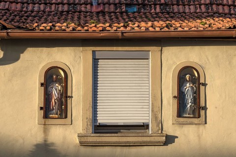 Figures of saints on a house facade in niches behind glass