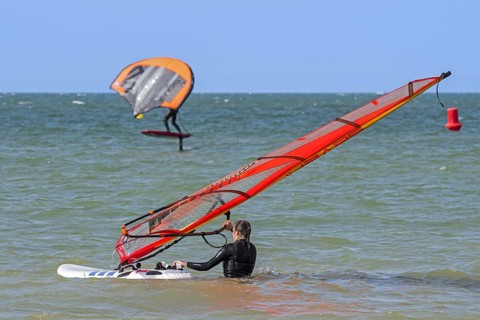 Female windsurfer entering the water and wingboarder