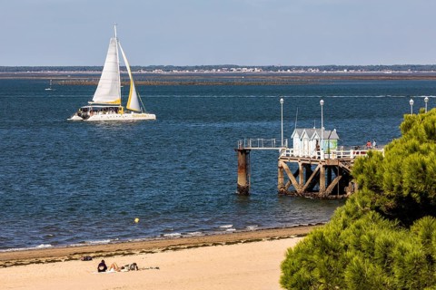 Sailboat in front of jetty and beach in Arcachon