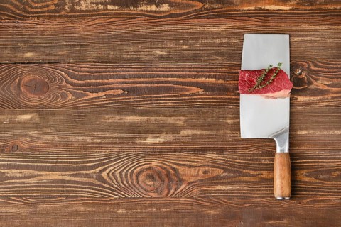 Piece of raw beef brisket flat steak on butcher's cleaver with place for text