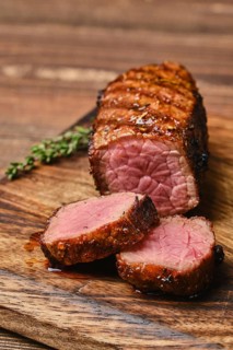 Closeup view of juicy roasted beef brisket flat steak on wooden cutting board