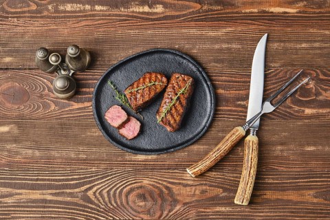 Top view of grilled beef steaks on wooden serving board