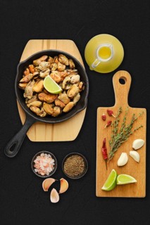 Boiled mussels and spice ready for frying on black background