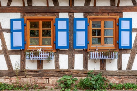 Half-timbered house with mullioned windows and blue shutters