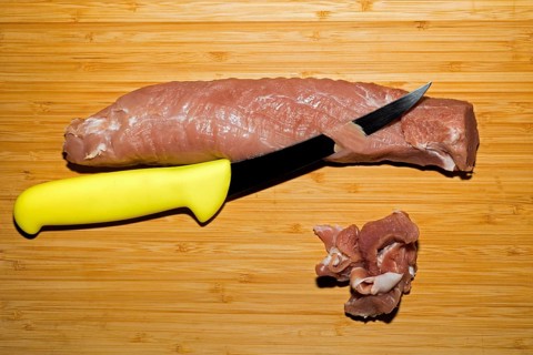 Pork fillet is freed from the silver skin with a knife