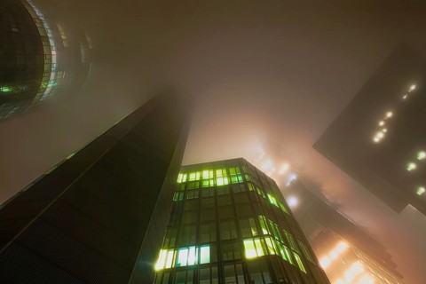 Illuminated skyscrapers in the fog at night