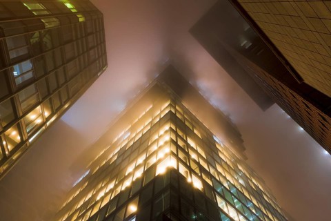 Illuminated skyscrapers in the fog at night