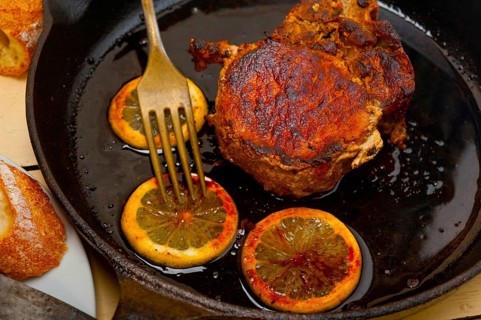 Pork chop seared on iron skillet with lemon and spices seasoning
