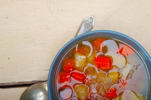 Traditional Italian minestrone soup on a rustic table with ingredients