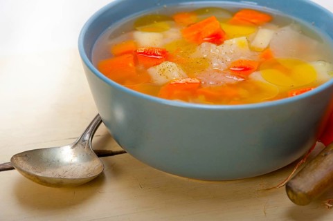 Traditional Italian minestrone soup on a rustic table with ingredients