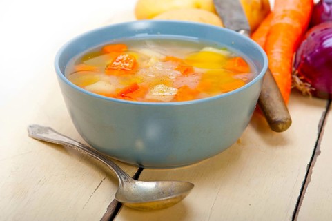Traditional Italian minestrone soup on a rustic table with ingredients