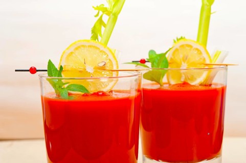Fresh tomato juice gazpacho soup on a glass over white wood table