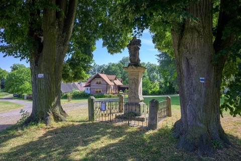 Sculpture of the Holy Trinity and old wooden house