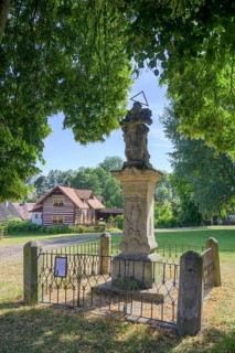 Sculpture of the Holy Trinity and old wooden house